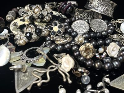 un tas de bijoux en argent posés sur une surface noire