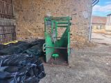 a green forklift parked in front of a brick wall
