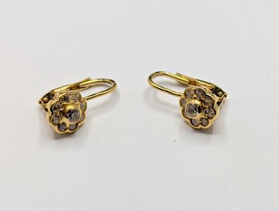 two pairs of gold and diamond earrings on a white surface