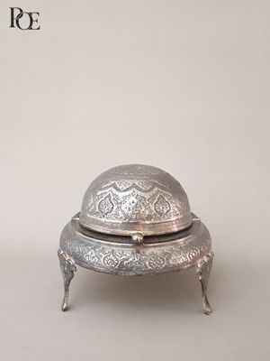 un plat ancien en argent avec un couvercle bombé, posé sur une table