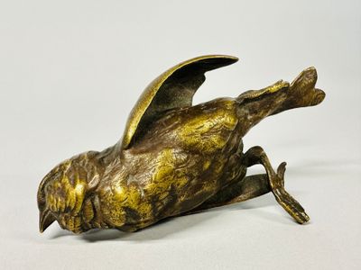 bronze sculpture of a bird on a white surface with a white background