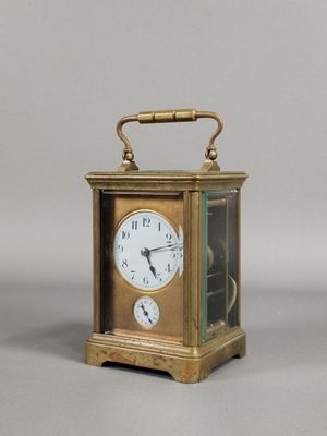 une petite horloge en laiton surmontée d'une vitrine