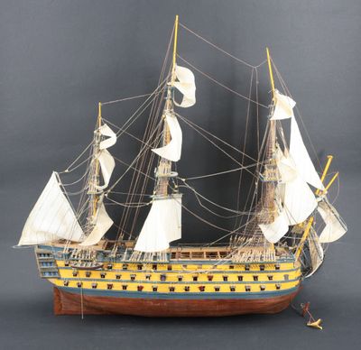 une vieille maquette en bois représentant un voilier posée sur une surface grise