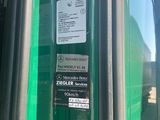 a green bus parked at a bus stop with its door open