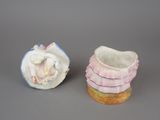 pair of porcelain figurines of a baby in a basket and a baby in a crib