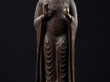 une statue de Bouddha debout sur un socle, sur fond noir