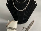 silver necklace, bracelet, and ring on a display stand
