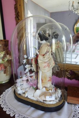 une figurine représentant une femme, placée sous une cloche en verre sur une table