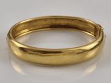 a close up of a gold bang bracelet on a white surface