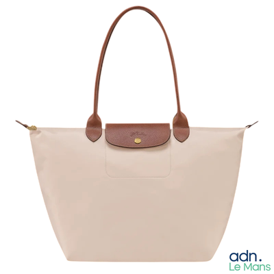 Le sac Longchamp est muni d'une poignée en cuir et est de couleur beige et marron.