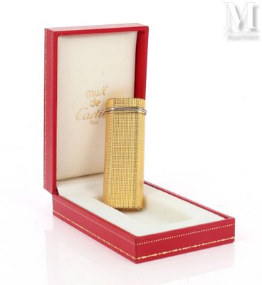 une image représentant un briquet doré dans une boîte rouge posée sur une surface blanche