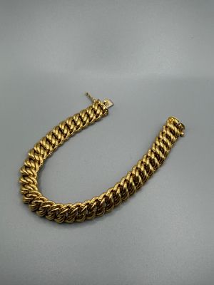 un bracelet en chaîne d'or avec un fermoir sur fond gris
