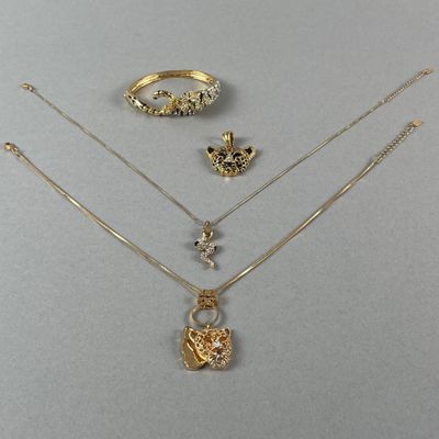trois colliers en or, une bague et une autre bague posées sur une table