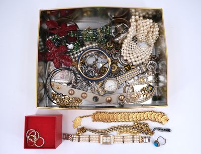 une boîte remplie de bijoux posée sur une table, à côté d'une boîte rouge