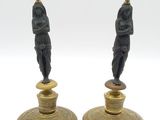 paire de bougeoirs anciens en laiton ornés de figurines représentant un homme et une femme