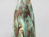 un vase vert et marron posé sur une surface grise