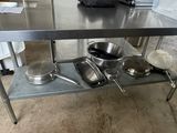 a stainless steel table with pots and pans on it