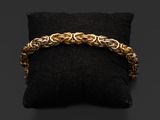 un bracelet en chaîne d'or posé sur un coussin noir