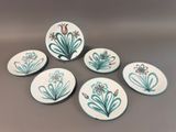 four plates with flowers painted on them sitting on a table
