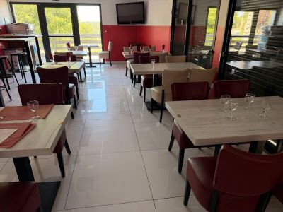 Dans un restaurant offrant une vue sur l'extérieur, les tables et les chaises sont alignées.