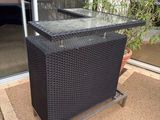 a black wicker bar with a glass top in front of a building