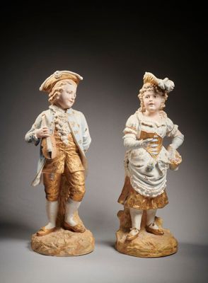 two figurines of a boy and a girl standing next to each other