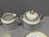 four pieces of white and gold china sitting on a table