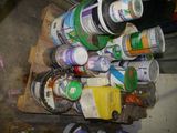 several cans of paint are stacked on a pallet in a garage