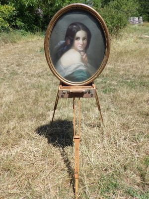 une image représentant un tableau d'une femme posée sur un chevalet dans un champ