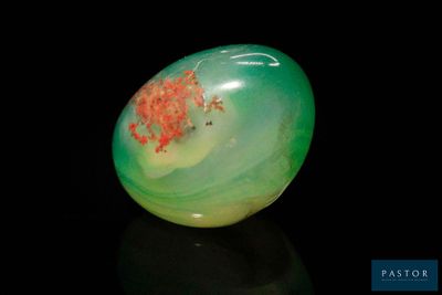 an image of a green and red stone on a black surface
