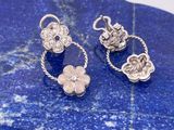 deux breloques en forme de fleur argentées posées sur une pierre bleue avec un fond blanc