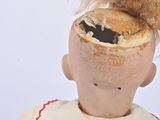 a teddy bear sitting on top of the head of a doll