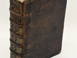 an old book sitting on top of a white table next to a white wall