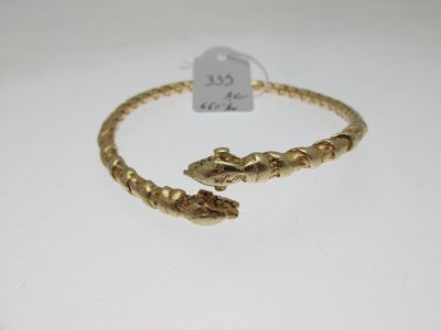 gros plan d'un bracelet en or sur une surface blanche