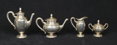 three silver teapots and a coffee pot on a black background