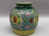 un vase vert et jaune posé sur une surface blanche