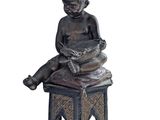 statue of a child sitting on a stool reading a book
