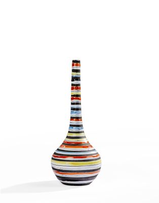 un vase à rayures multicolores posé sur une surface blanche