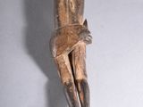 wooden sculpture of a man sitting on a cross with his hands on his knees