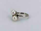 a close up of a ring with two pearls on it