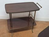 a wooden and brass serving cart with two trays on it