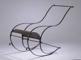 un fauteuil à bascule en fer avec une assise en bois, posé sur une surface blanche