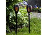 two black torches in the grass with flowers in the background