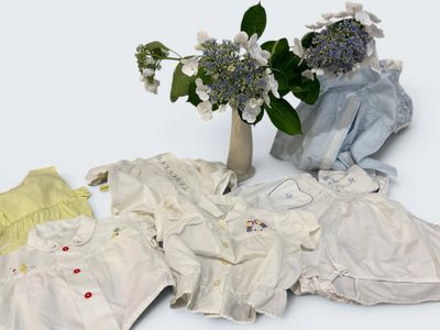 a bunch of baby clothes and a vase of flowers on the table