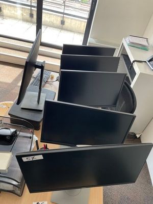 trois écrans d'ordinateur posés sur un bureau dans un bureau