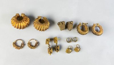 a lot of gold rings and earrings on a white surface