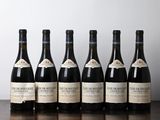 six bottles of wine sit on a table in front of a wall