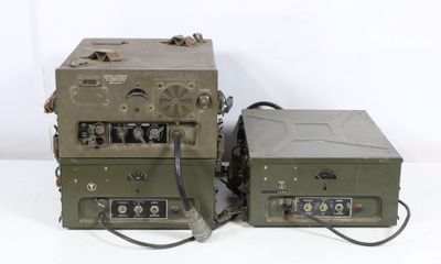 two old military radio equipment sitting on a white surface