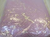 a pink sheet with gold foil on it on a wooden floor