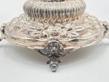 a silver plate on a stand on a white surface